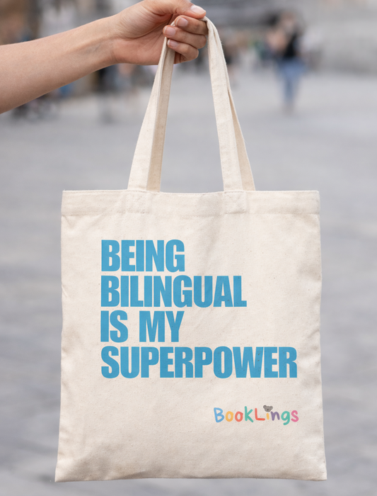 Tote bag with 'Being Bilingual is My Superpower' text held by a person outdoors.