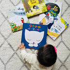 Child interacting with children's Simplified Chinese books on a textured floor